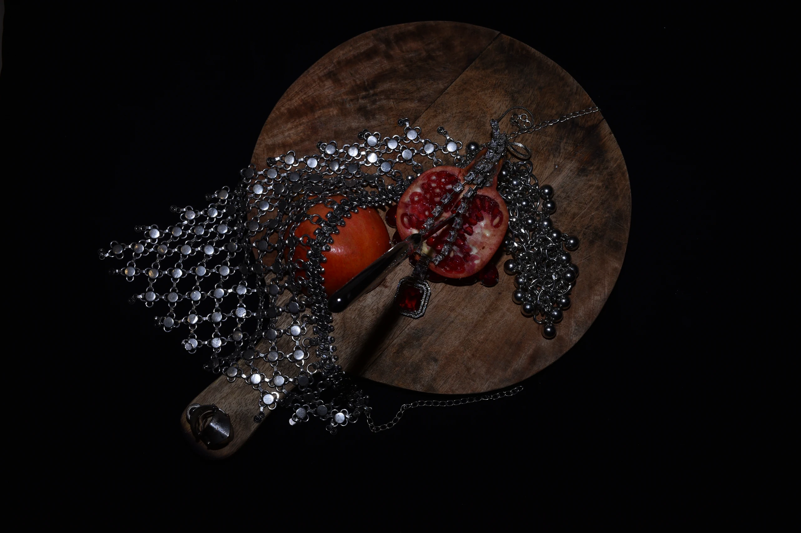 Silver jewellery and a ceremonial knife arranged with cut pomegranates in the AZU'S/ARC atelier.